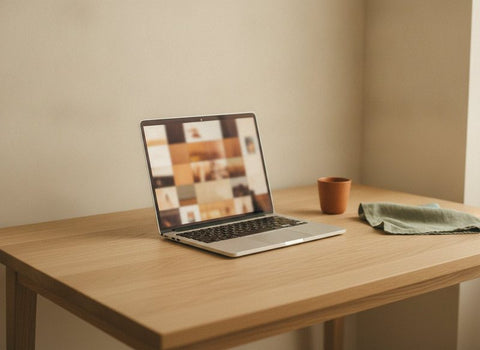 Laptop auf einem Schreibtisch zeigt ein unscharfes Foto-Mosaik beim Hochladen eigener Bilder